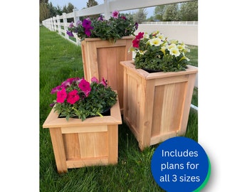 May include: Three wooden planter boxes in different sizes, with flowers in bloom. The boxes are made of cedar wood and have a natural finish. The largest box is on the left, followed by the medium box in the center, and the smallest box on the right. The boxes are sitting on a grassy lawn. The text "Includes plans for all 3 sizes" is visible in the lower right corner of the image.