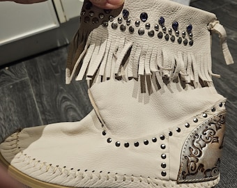 Botas estilo mocasín, vaqueras o western, de piel suave beige, estilo años 80, con flecos, adornos metálicos y borlas. Hechas en Italia. Talla 9 (40).