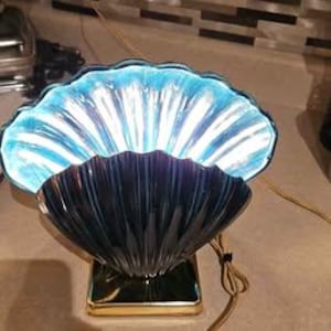 May include: A blue and iridescent seashell-shaped table lamp with a gold base.