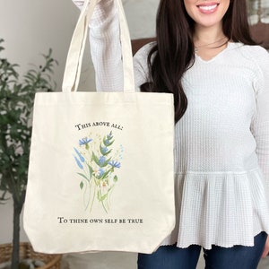 Pode incluir: Uma bolsa tote de lona branca com um design floral e o texto "This above all: To thine own self be true".