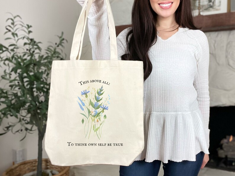 Pode incluir: Uma bolsa tote de lona branca com um design floral e o texto "This above all: To thine own self be true".