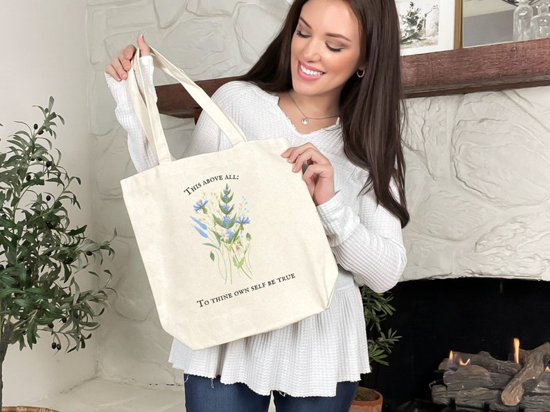 Pode incluir: Uma bolsa tote de lona branca com um design floral e o texto "This above all: To thine own self be true".