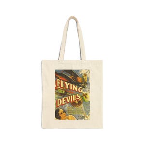 May include: A white canvas tote bag with a vintage movie poster design featuring a biplane and the text "Flying Devils". The poster is in red, yellow, blue, and green colors.