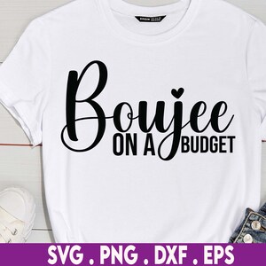 May include: White t-shirt with black text that reads "Boujee on a Budget" with a small heart above the word "Budget".