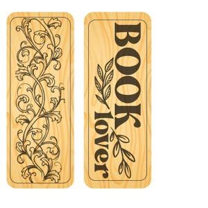 May include: Two wooden bookmarks. One features an intricate black floral design on a light wood grain background. The other bookmark has the words "BOOK lover" in black, with leaf accents. Both bookmarks have rounded corners.