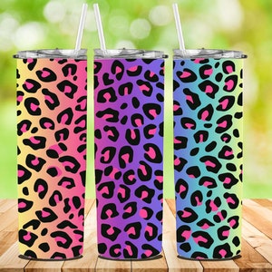 Puede incluir: Tres vasos de acero inoxidable con un diseño de estampado de leopardo degradado arcoíris. Los vasos están alineados en una fila de izquierda a derecha con los colores que pasan de amarillo a rosa, de morado a azul y de verde a rosa.