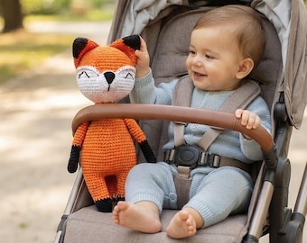 May include: A crocheted fox toy with bright orange yarn, a white muzzle, and black accents on the ears and paws. The stuffed animal features embroidered closed eyes and a black nose, crafted with a textured stitch pattern throughout its body.
