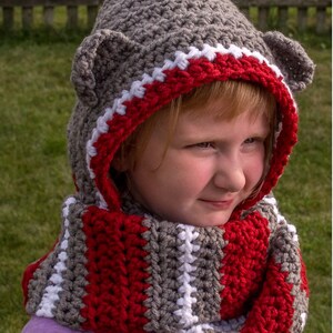 May include: Gray hooded scarf with red and white stripes. The hood has two small gray ears. The scarf is crocheted.