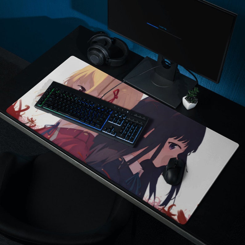 May include: A white mousepad with a colorful anime illustration of two girls with long black hair. The mousepad has a black keyboard and a black mouse on it.