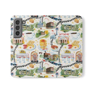 May include: A white smartphone case featuring a repeating watercolor pattern of Springfield landmarks, diners, jukeboxes, stacks of pancakes with syrup, coffee cups, and breakfast plates with eggs and bacon, connected by a black and white checkered road.