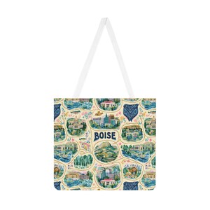 May include: A tote bag with white handles featuring a repeating pattern of Boise, Idaho landmarks, including the state capitol, city skyline, and natural scenery. The design includes the word BOISE in dark blue text amidst illustrations of trees, rivers, and blue bandana-style motifs on a cream background.
