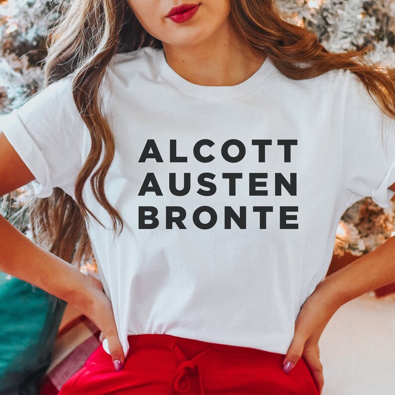 May include: White t-shirt with black text that reads "ALCOTT AUSTEN BRONTE".