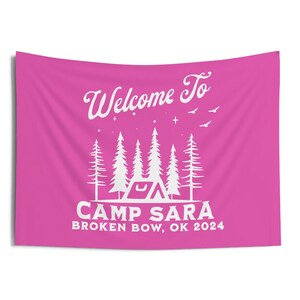 May include: Pink welcome banner with white text that reads "Welcome to Camp Sara Broken Bow, OK 2024". The banner features a stylized illustration of a tent and trees.