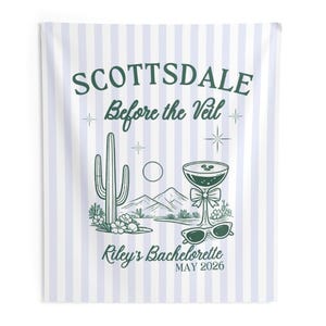 May include: A white and light blue striped wall hanging with the text "SCOTTSDALE Before the Veil" in green. The design includes a cactus, mountains, a cocktail, sunglasses, and the text "Riley's Bachelorette MAY 2026".