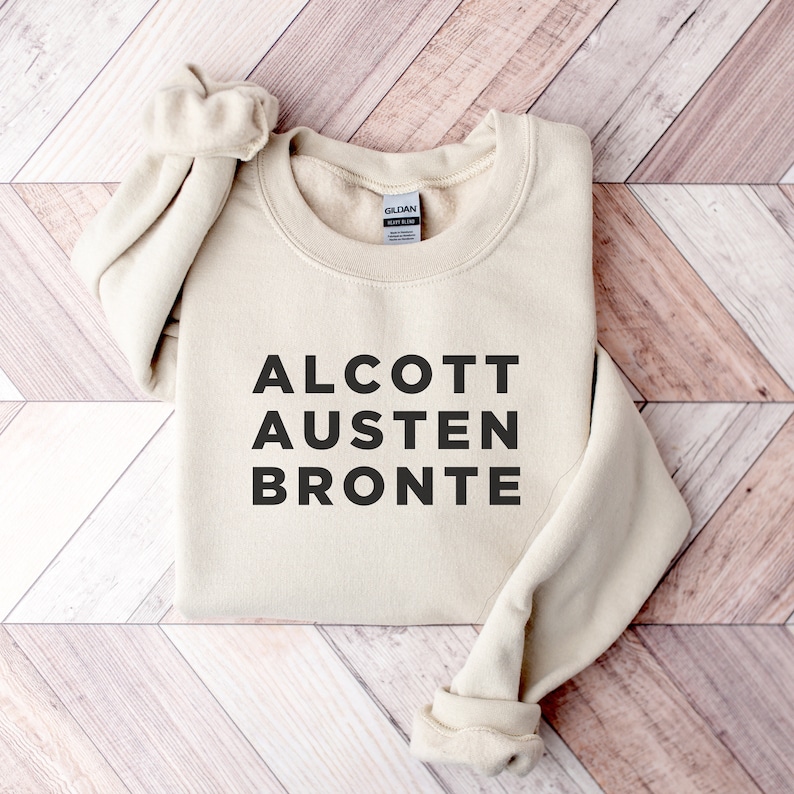 May include: A beige sweatshirt with the text "ALCOTT AUSTEN BRONTE" printed in black.