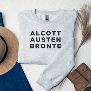 May include: Gray sweatshirt with the text "ALCOTT AUSTEN BRONTE" printed in black.