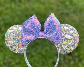 Peut inclure: Noeud en sequins violet et rose avec des strass irisés sur un serre-tête bleu clair.