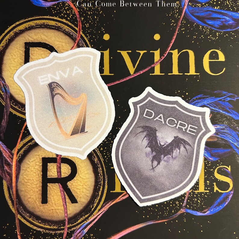 May include: Two shield-shaped stickers with different designs. The first sticker is white with a gold harp and the text "ENVA". The second sticker is grey with a black bat and the text "DACRE".
