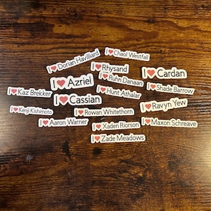 May include: A collection of stickers with the text "I love" followed by various names, including "Dorian Havilliard", "Chaol Westfall", "Rhysand", "Cardan", "Azriel", "Ruhn Danaan", "Cassian", "Hunt Athalar", "Shade Barrow", "Kaz Brekker", "Rowan Whitethorn", "Ravyn Yew", "Kenji Kishimoto", "Aaron Warner", "Xaden Riorson", "Maxon Schreave", and "Zade Meadows".