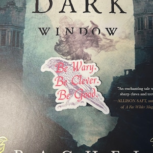 May include: A white sticker with a black and white illustration of a raven. The raven has red text that says "Be Wary. Be Clever. Be Good."