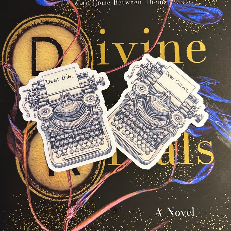 May include: Two vintage typewriter stickers with the text "Dear Iris" and "Dear Carver" on them. The stickers are on a black background with a gold and blue design.