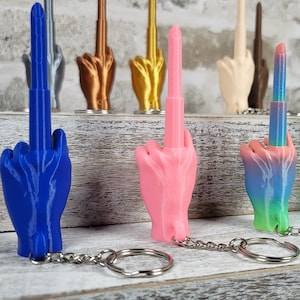 May include: A set of seven colourful middle finger keychain charms. The charms are made of plastic and are attached to silver keychains. The charms are in various colours, including blue, pink, green, and rainbow.