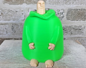 May include: A bright green 3D printed figurine of a person wearing a hooded robe. The figurine has a simple face and is sitting with its hands in its lap.