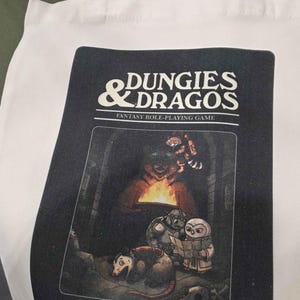 Peut inclure: Une tasse en céramique blanche avec une anse noire et le texte "But First, Coffee" en noir, dans une police manuscrite. La tasse est posée sur une surface blanche.