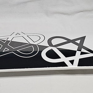 May include: A skateboard with a white deck featuring a black and white graphic design. The skateboard has white trucks and pink wheels. The wheels have a star design. The skateboard is designed for recreational use.