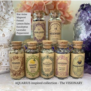 May include: A collection of seven small glass jars with cork stoppers, each containing dried herbs labeled Star Anise, Mugwort, Fennel, Lemon Balm, Eucalyptus, Lavender, and Peppermint. The labels feature ornate, vintage-style typography and decorative borders.