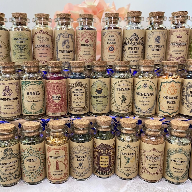 May include: A collection of small glass apothecary jars with cork stoppers, each containing dried herbs or spices. The jars feature vintage-style tan paper labels with botanical names, scientific names, and decorative illustrations.