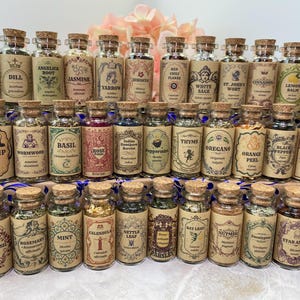 May include: A collection of small, clear glass apothecary jars with cork stoppers, each filled with dried herbs or spices. Every jar features a vintage-style tan paper label with ornate borders, botanical illustrations, and the name of the herb.