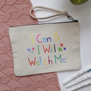 May include: A white canvas zippered pouch with a black zipper and a black handle. The pouch has the text "I Can & I Will Watch Me" written in colourful, handwritten-style font.