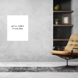 May include: A white square print with the text "get 1% better every day" in black lettering.