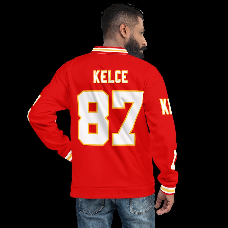Puede incluir: Jersey de manga larga rojo y dorado con el nombre "KELCE" y el n&uacute;mero "87" en la espalda.