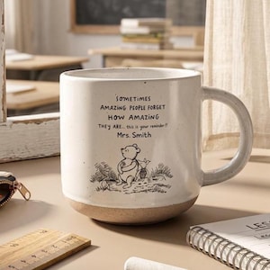May include: A speckled white ceramic mug with a handle, featuring a black line drawing of Winnie the Pooh and Piglet, along with the text: Sometimes amazing people forget how amazing they are... this is your reminder!! Mrs. Smith.