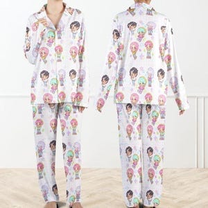 May include: White pajama set with a repeating cartoon character pattern in various colors. The long-sleeved top has a button-down front and a collar. The matching pants have a straight leg design. The pajamas are made of a soft, lightweight fabric.