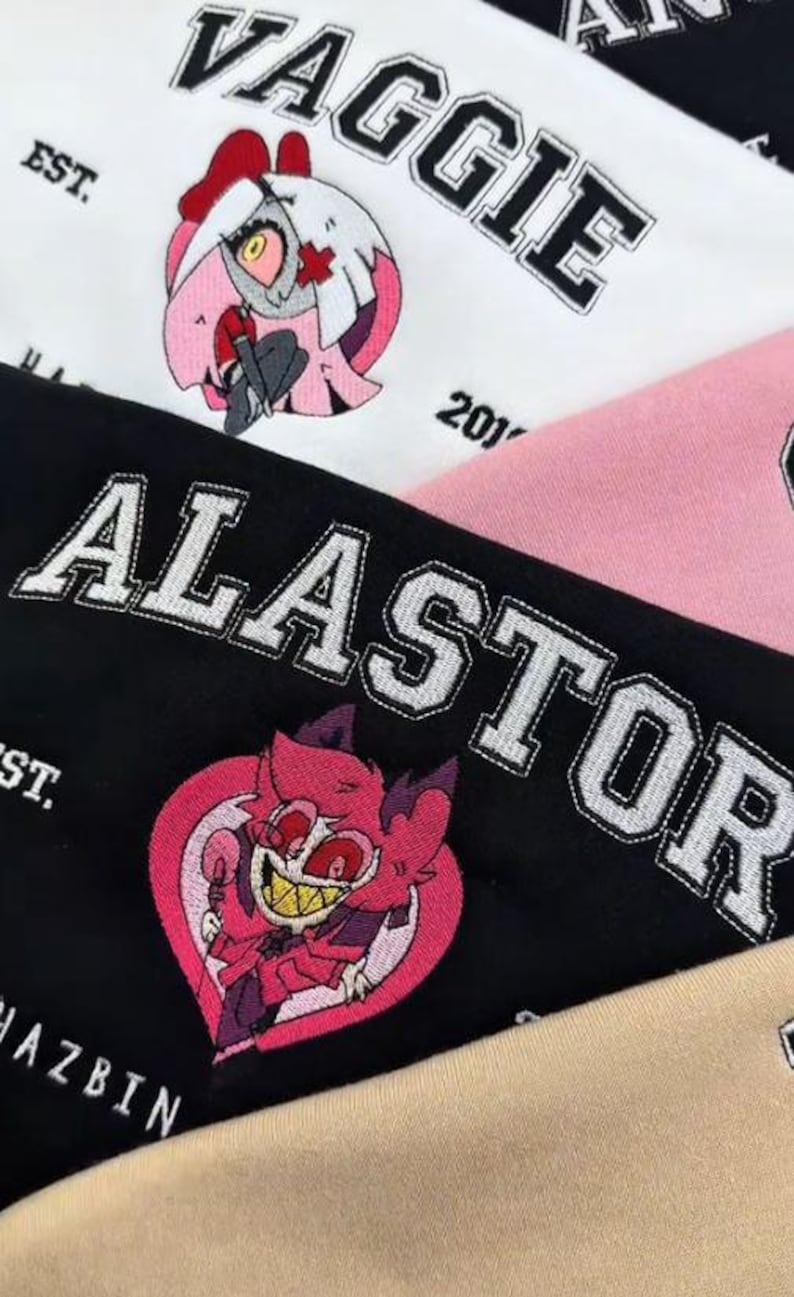 Pode incluir: Close-up de tecido bordado com personagens de desenhos animados e texto. A palavra "VAGGIE" &eacute; costurada em letras pretas sobre um fundo branco, com um personagem de desenho animado. A palavra "ALASTOR" &eacute; costurada em um fundo preto.