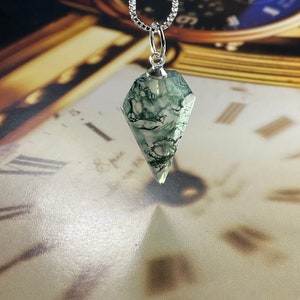 May include: A silver chain necklace with a green and white agate pendant shaped like a diamond. The pendant is a crystal point.