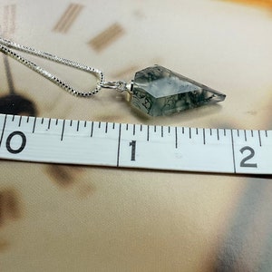 May include: A silver chain necklace with a grey and black dendritic agate pendant shaped like a point. The pendant is approximately 2.5 cm long.
