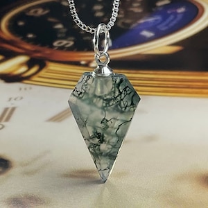 May include: A silver chain necklace with a green and white moss agate pendant shaped like a diamond. The pendant is faceted and has a silver bail.