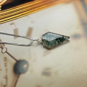 May include: A silver chain necklace with a green and white agate pendant in the shape of a point.