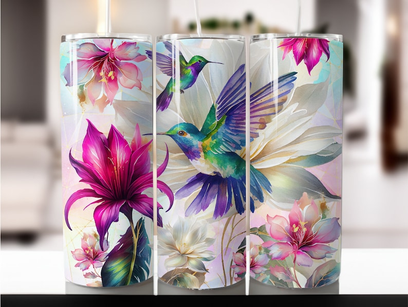 May include: A stainless steel tumbler with a colorful design featuring hummingbirds and flowers. The design is a watercolor style with pink, purple, green, and blue colors.