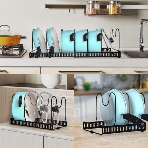 May include: A black metal pan organiser with a tiered design to store pots and lids. The organiser is shown with blue pots and lids.