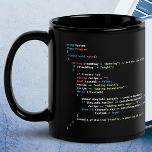 May include: Black coffee mug with a white design of code on it. The code reads "using System; class Program { static void Main() { string timeOfDay = "morning"; // Set the time of day if (timeOfDay != "night") { // Prepare tea string recipe = ""; bool tasteok = false; recipe += "Adding tea
"; recipe += "Adding hotwater
"; while (!tasteok) { ConsoleKeyInfo keyInfo = Console.ReadKey(); if (keyInfo.KeyChar == ConsoleKey.Spacebar) { recipe += "Adding more sugar...
"; } else if (keyInfo.Key == ConsoleKey.Enter) { tasteok = true; } } Console.WriteLine("Finally, a good cup of tea!"); } } }"