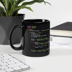 May include: Black coffee mug with a white design of code on it. The code includes the text "#include <iostream>" and "#include <sstream>" and "int main() { ".