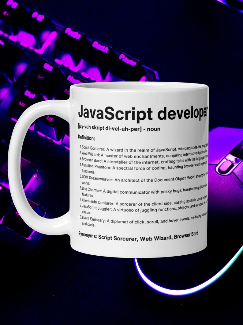 Pu&ograve; includere: Una tazza in ceramica bianca con un manico nero. La tazza presenta una grafica in bianco e nero con il testo "JavaScript developer" e una definizione del termine. La definizione include sinonimi: "Script Sorcerer, Web Wizard, Browser Bard".