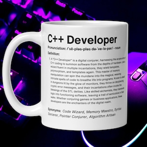 Może przedstawiać: Biały kubek ceramiczny z czarnym uchwytem. Kubek ma czarno-biały wzór z tekstem "C++ Developer" i definicją tego terminu. Kubek stoi na fioletowym keyboardzie.