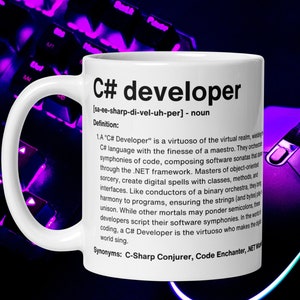 Może przedstawiać: Biały kubek ceramiczny z czarno-białym wzorem. Kubek zawiera definicję "programisty C#" wraz z wymową i synonimami. Kubek to świetny prezent dla każdego programisty C#.