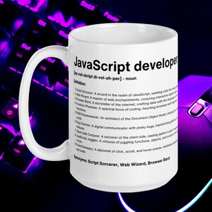 Pu&ograve; includere: Una tazza in ceramica bianca con un designo nero che definisce uno sviluppatore JavaScript come un "mago nel regno di JavaScript". La tazza ha un manico nero e si trova su una tastiera viola.